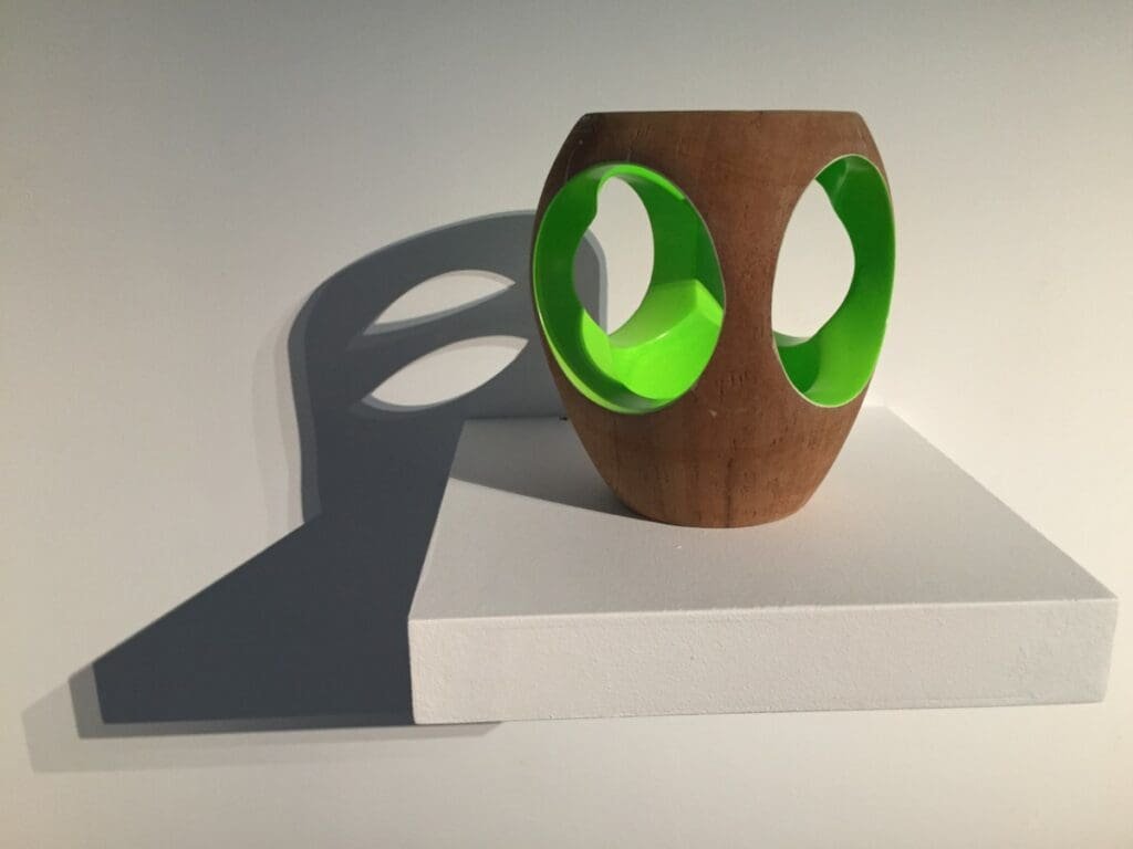 Expo Yom de Saint Phalle -DR Valérie Collet 2019 Sculpture bois et plastique vert vif avec ombre projetée sur socle blanc.