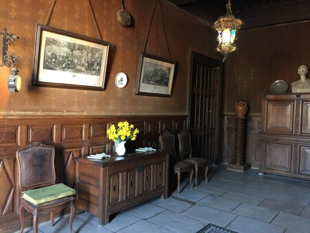 Intérieur boisé Maison de Lamartine Milly avec meubles anciens et fleurs jaunes.