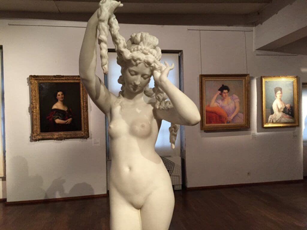 Musée des Ursulines -DR Valérie Collet 2019 Sculpture en marbre d'une femme nue au musée des Ursulines, entourée de tableaux.