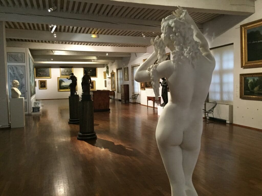 Musée des Ursulines -DR Valérie Collet 2019 Statue blanche de dos dans une salle du Musée des Ursulines avec peintures.