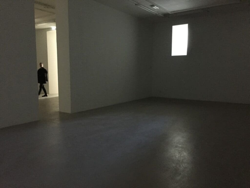 Intérieur d'exposition sombre avec une silhouette marchant dans l'ouverture.