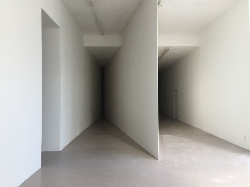 Intérieur moderne blanc, perspective d'un couloir étroit menant à l'obscurité.