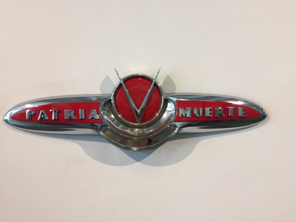 Insigne chromé "Patria Muerte" avec emblème central, œuvre d'art à La Havane.
