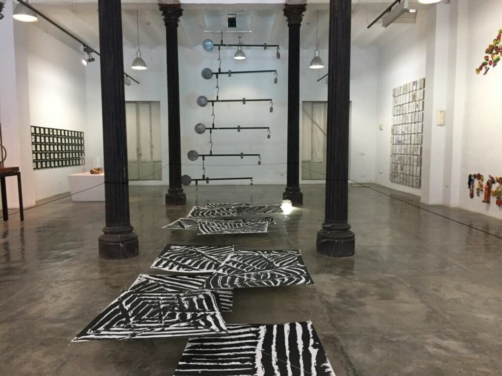 Installation contemporaine à la Factoría Habana avec œuvres noires et blanches au sol.