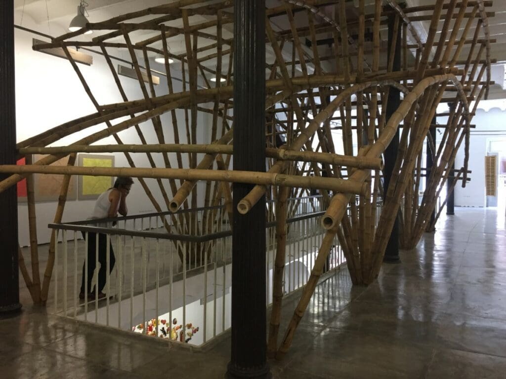 Installation en bambou à la Factoria Habana avec une visiteuse observant l'œuvre.