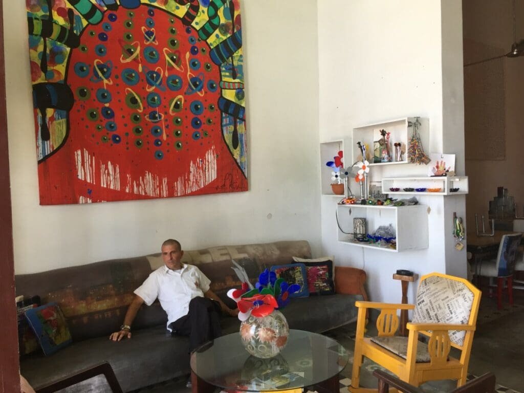 Homme assis sur un canapé sous une grande œuvre d'art rouge à l'hôtel Malecon 663, La Havane.