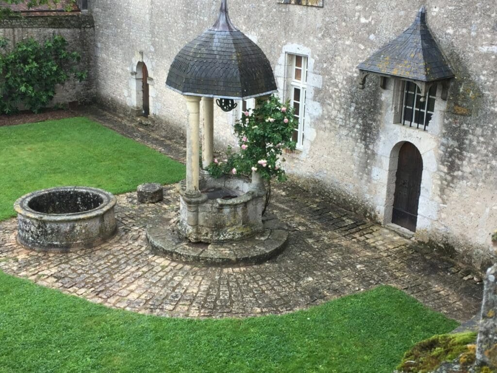 Puits et rosier dans la cour pavée du château de Talcy, Val de Loire.