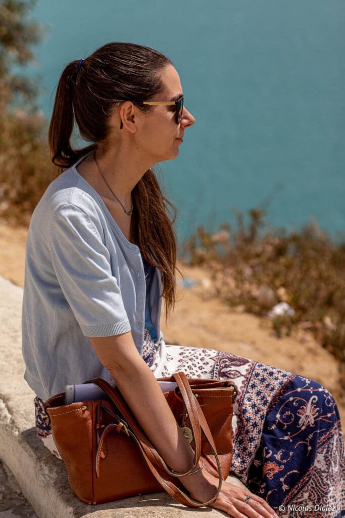 Femme assise avec sac en cuir et vue mer bleu turquoise à Sidi Bou Saïd