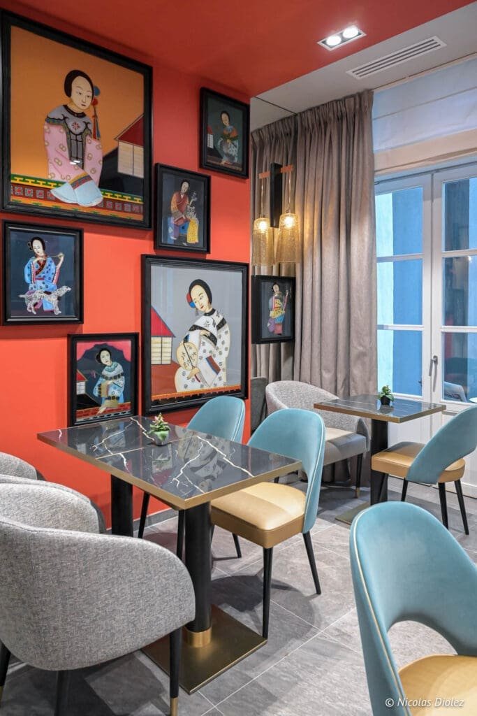 Coin salon de l'Hôtel La Lanterne avec tableaux asiatiques mur corail.