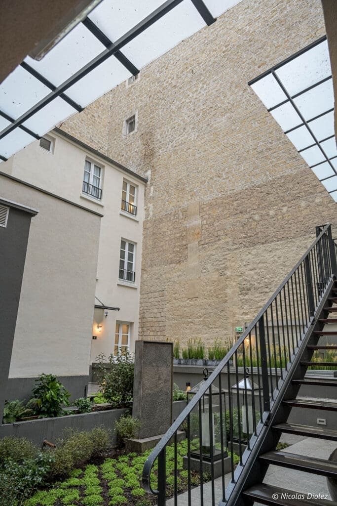 Escalier extérieur et cour intérieure végétale de l'Hôtel La Lanterne Paris.
