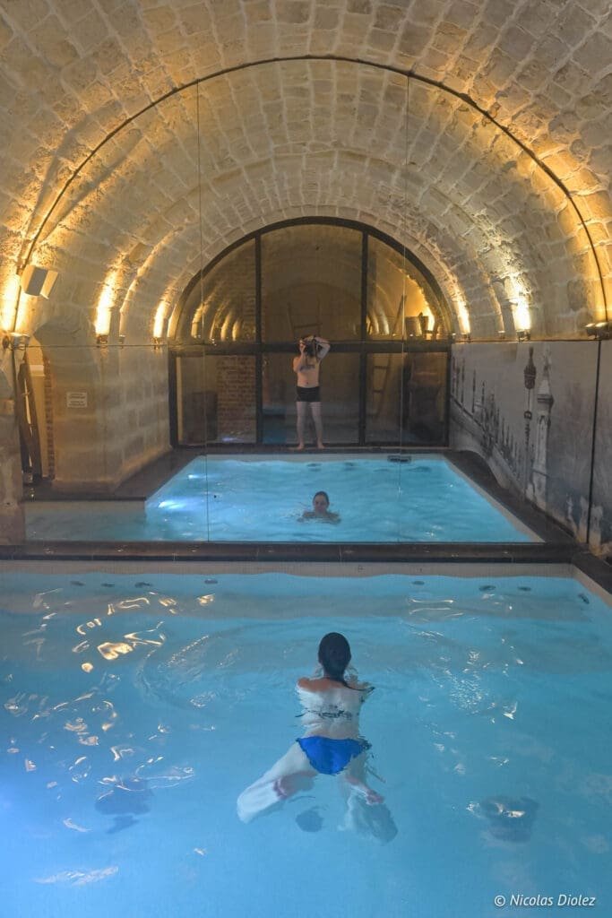 Piscine intérieure voûtée Hôtel La Lanterne Paris avec baigneurs.