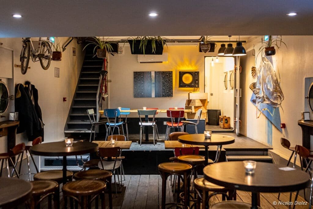 Intérieur péniche bar à vin La Bougeotte avec tables hautes et vélos suspendus.