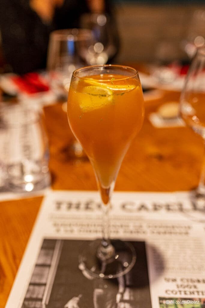 Cocktail aux agrumes dans un verre à pied sur menu de restaurant La Malle aux Épices.