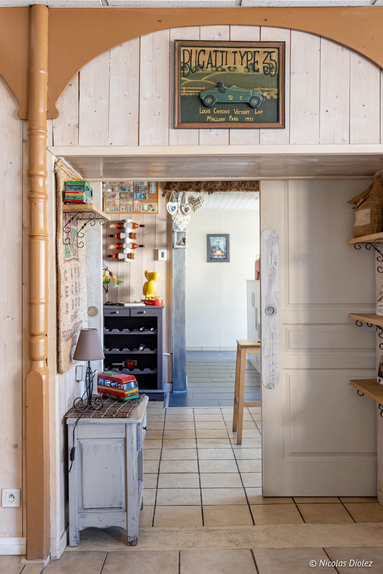 Intérieur rustique avec panneau Bugatti Type 35 et passage vers une autre pièce.