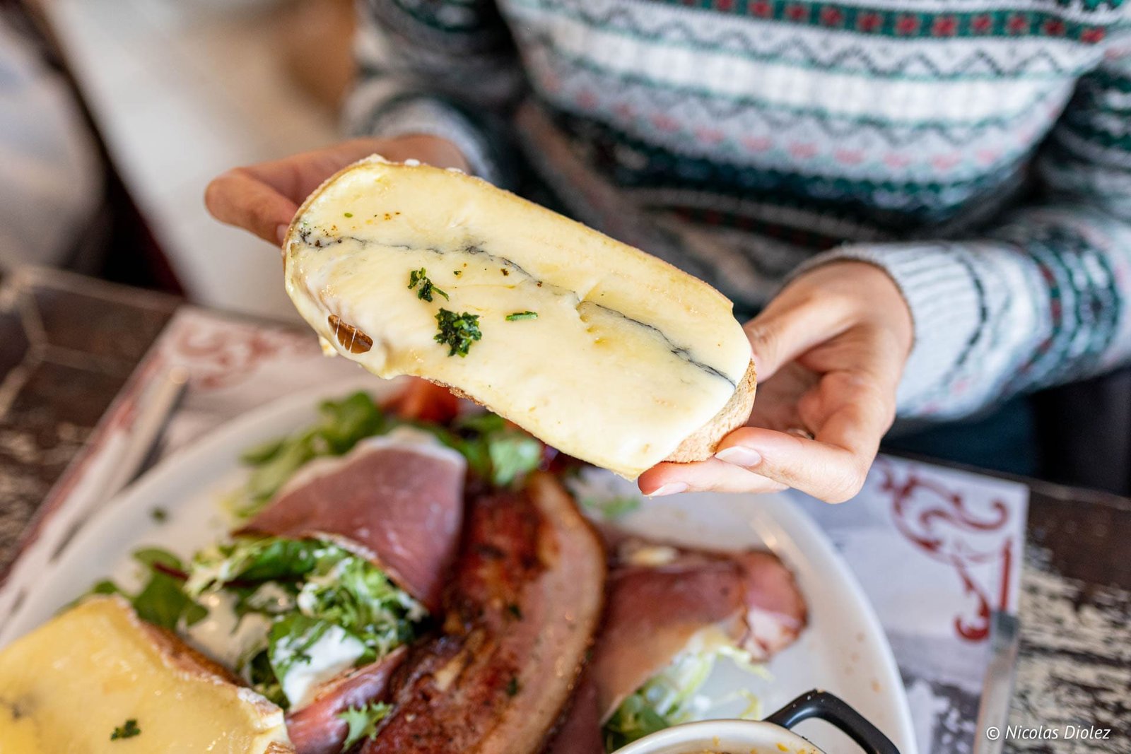 Tranche de pain avec fromage fondu aux herbes et bleu, servie avec charcuterie et salade.