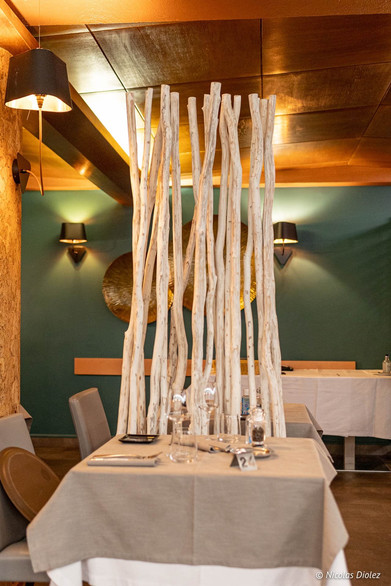 Intérieur restaurant Hôtel Beau Site Luxeuil-les-Bains avec paravent en branches blanches.