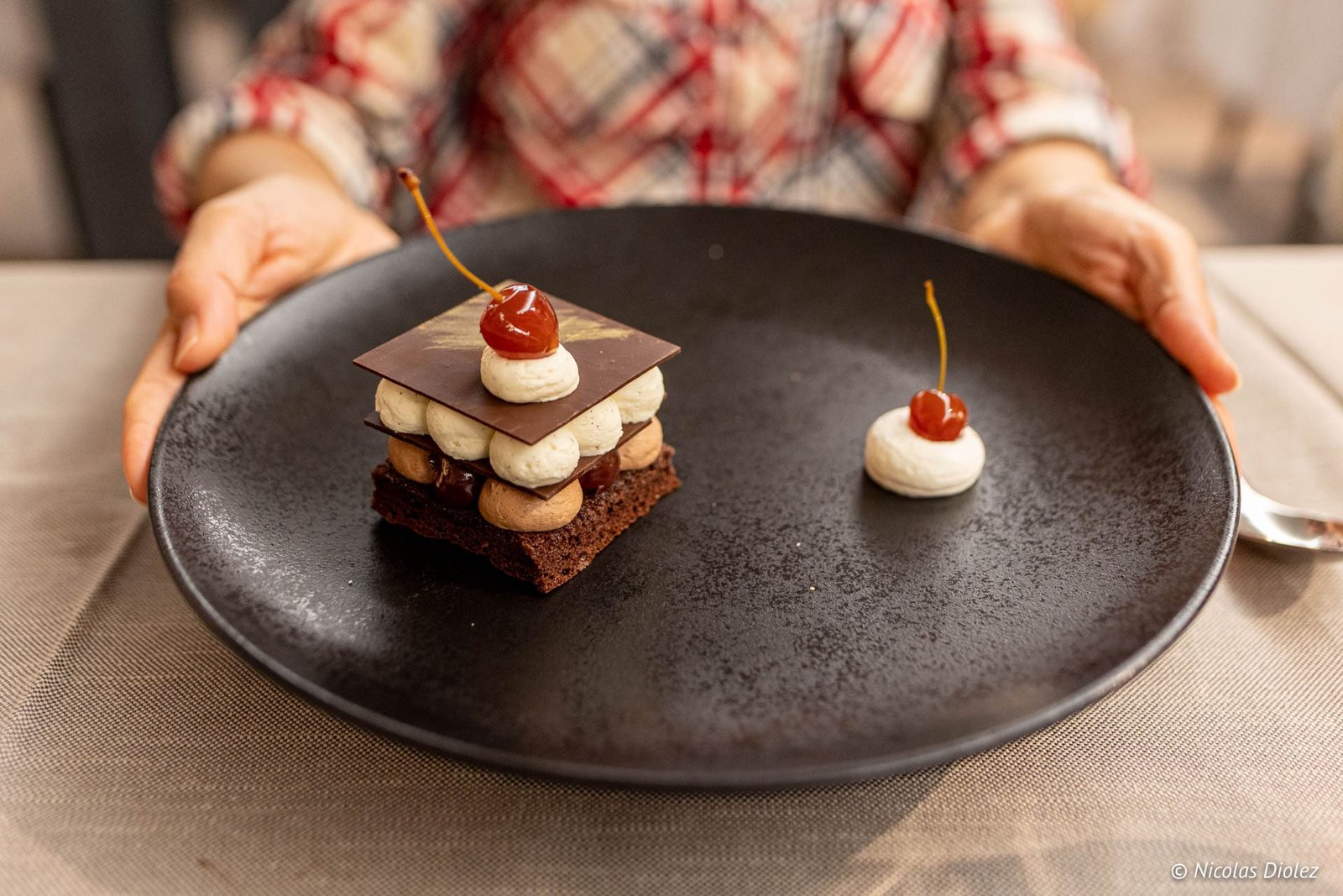 Dessert chocolaté aux cerises présenté sur assiette noire à l'Hôtel Beau Site Luxeuil.