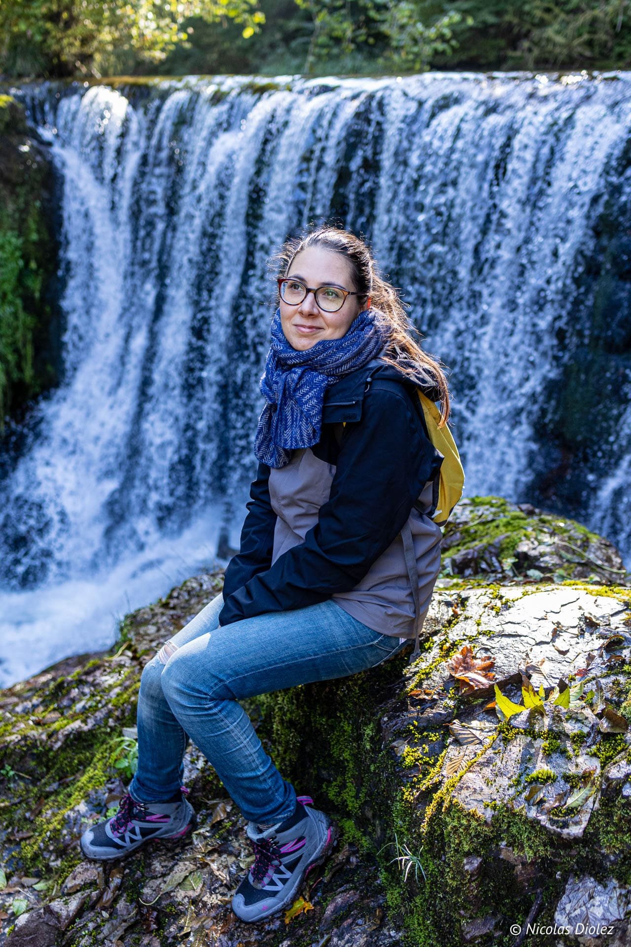 Randonneuse assise près d'une cascade dans les Vosges du Sud.