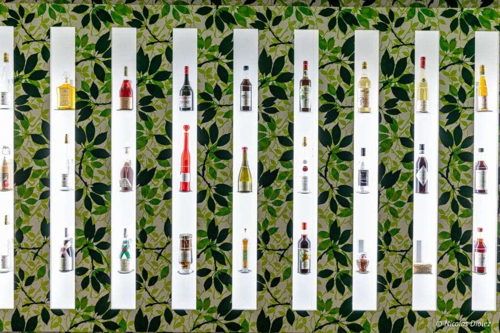 Écomusée du Pays de la Cerise : étagères éclairées présentant diverses bouteilles d'alcool.