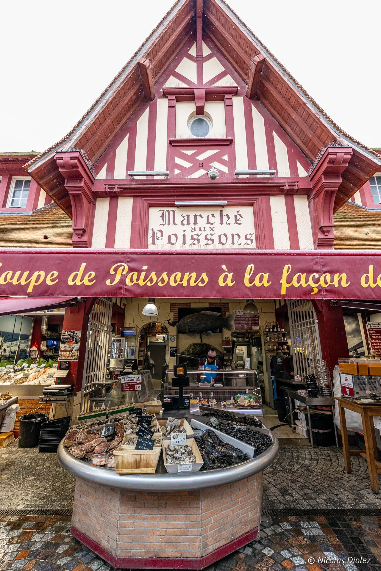 Marché aux Poissons de Trouville avec étalage de fruits de mer et enseigne rouge.