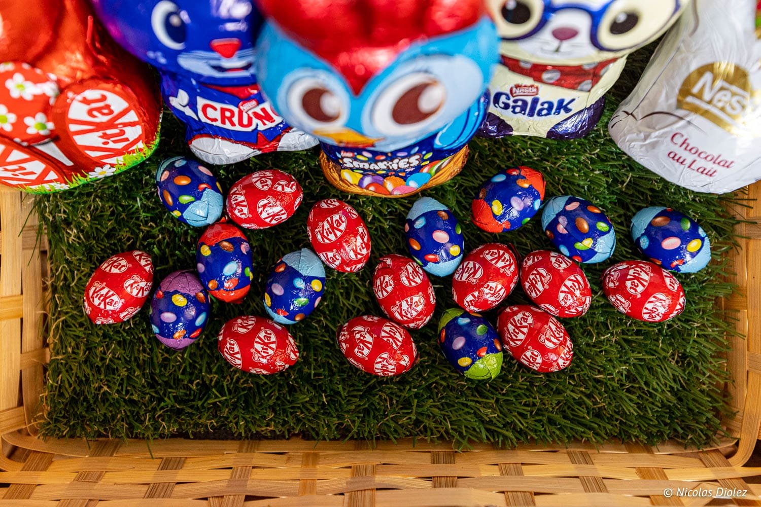 Nestlé Easter chocolates, KitKat and Smarties eggs on synthetic grass in a basket.