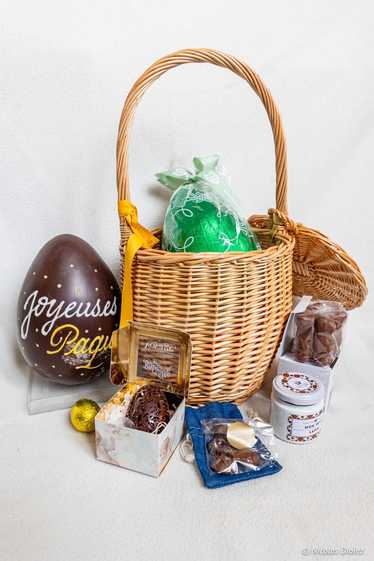 Easter wicker basket with "Happy Easter" eggs and chocolates.