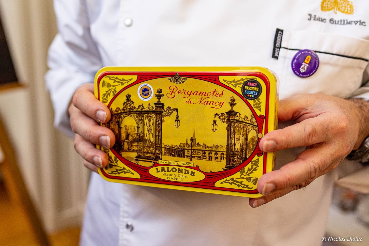 Boîte de Bergamotes de Nancy par Lalonde, tenue par un chef en veste blanche.