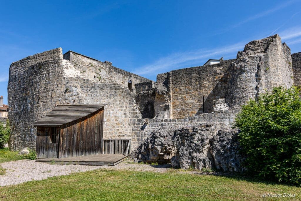 Forteresse de Châtel-sur-Moselle, ruines en pierre avec abri en bois et ciel bleu.