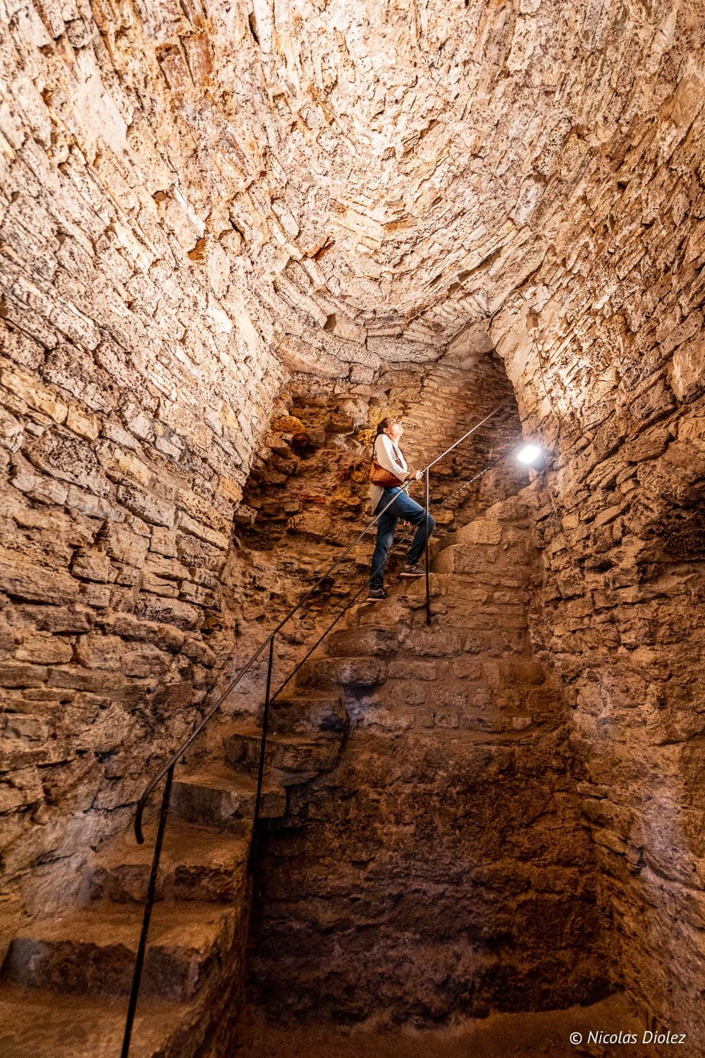 Touriste montant l'escalier en pierre de la forteresse de Châtel-sur-Moselle.