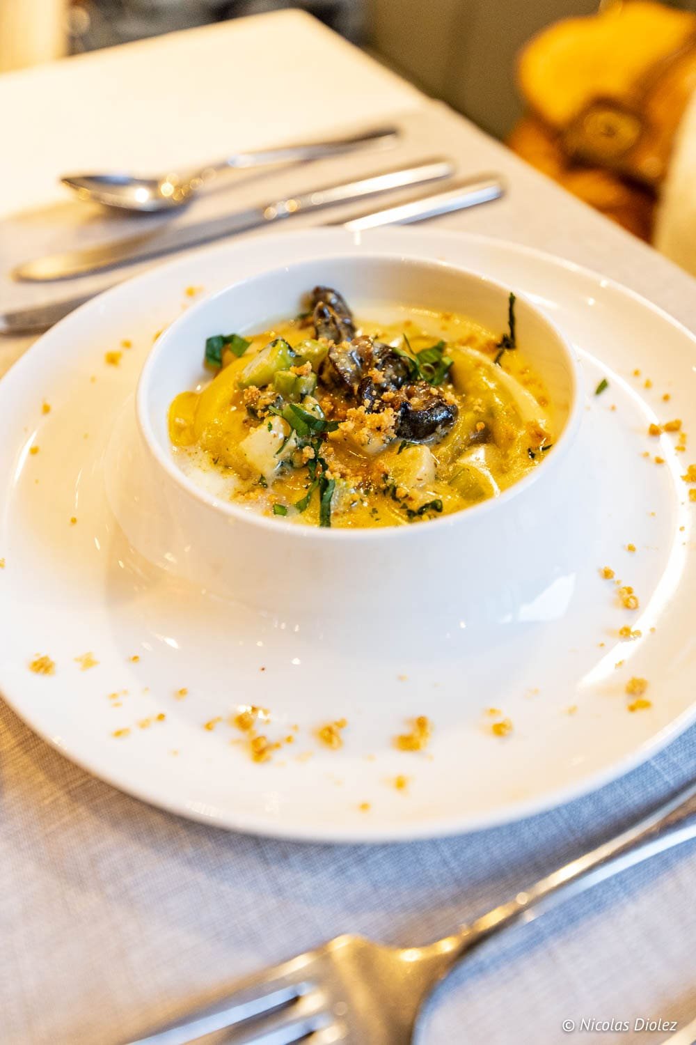 Ravioles sauce crème aux champignons et herbes sur assiette blanche à Épinal.