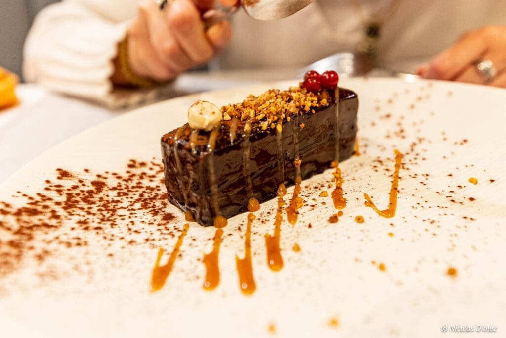 Glaçage chocolat, noisettes et fruits rouges sur dessert, saupoudré de cacao.