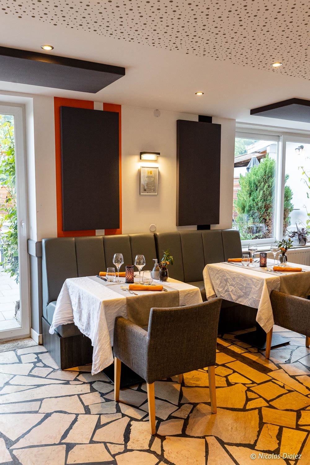 Intérieur restaurant La Chaumière Chantraine avec tables dressées et banquette.