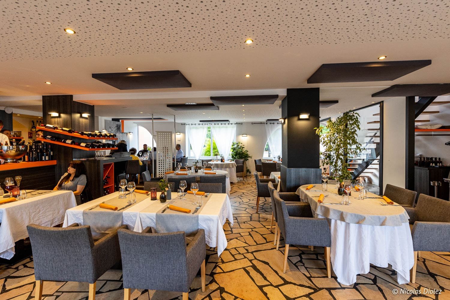 Intérieur restaurant moderne avec tables dressées et rangements à vin, La Chaumière Chantraine.