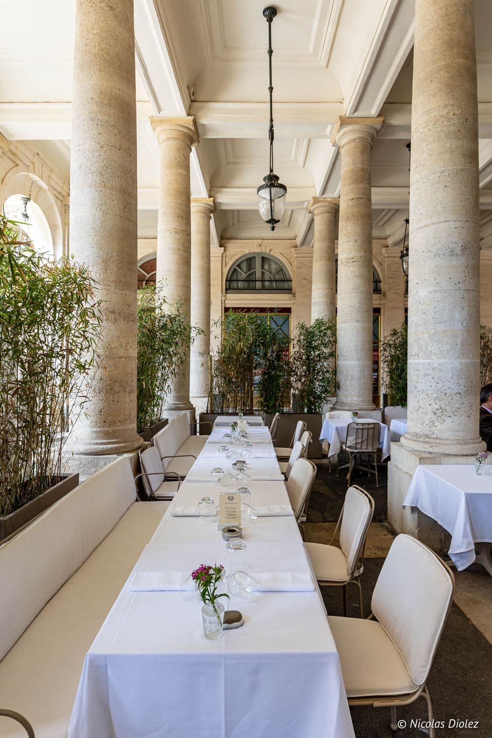 Terrasse couverte du Grand Véfour avec tables dressées sous des colonnes.