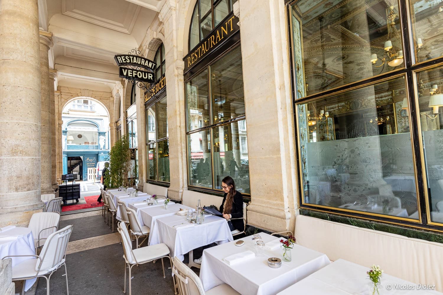 Terrasse extérieure du Restaurant Le Grand Véfour avec tables dressées sous arcades.