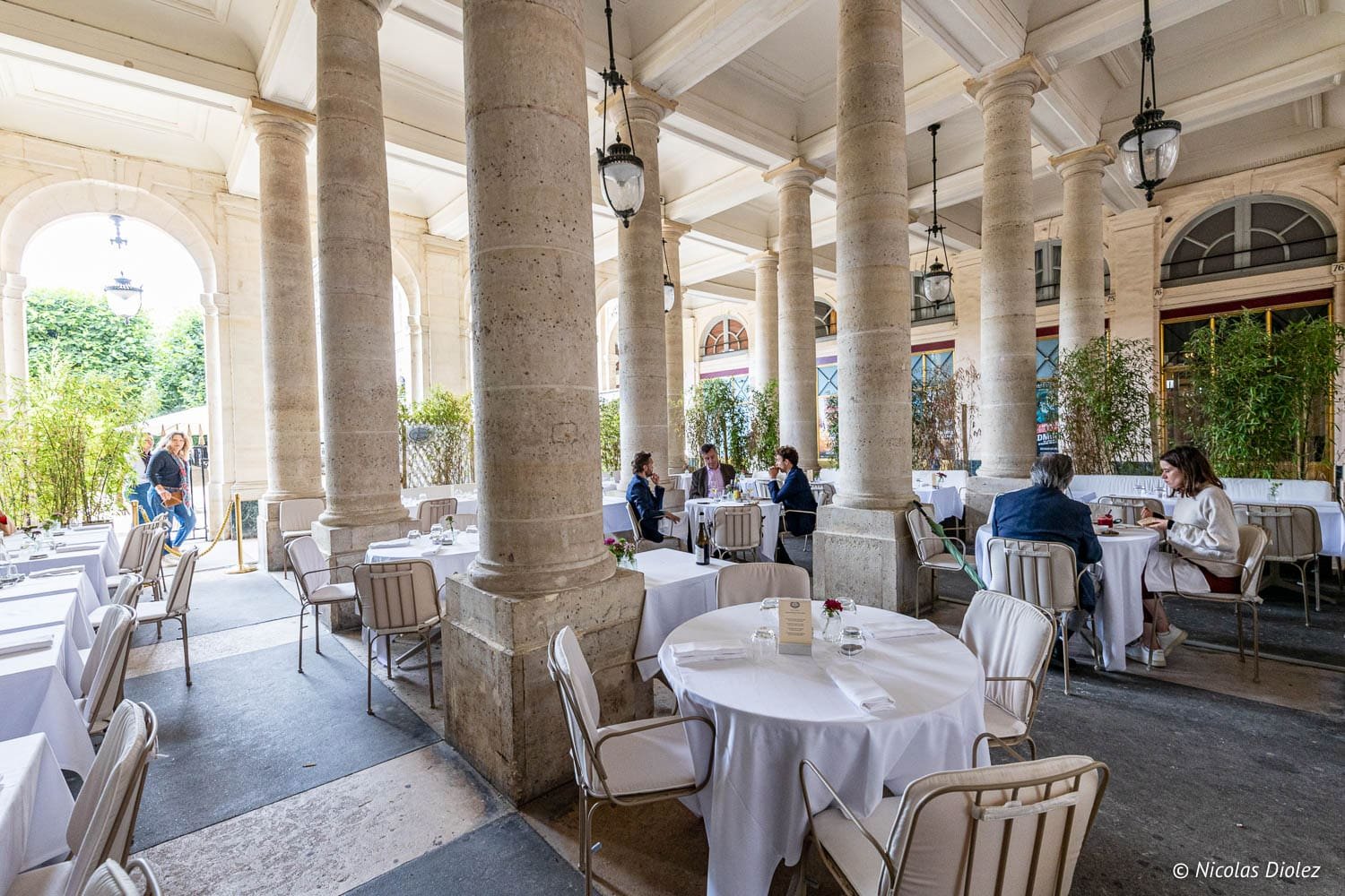 Terrasse couverte du Grand Véfour avec colonnes et tables nappées de blanc.
