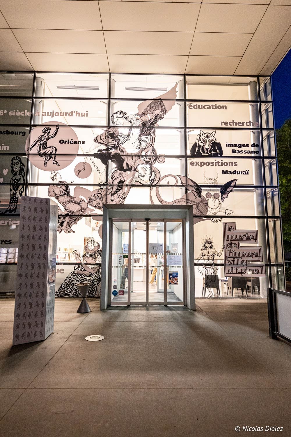 Extérieur nocturne du Musée de l'Image d'Épinal avec illustrations.