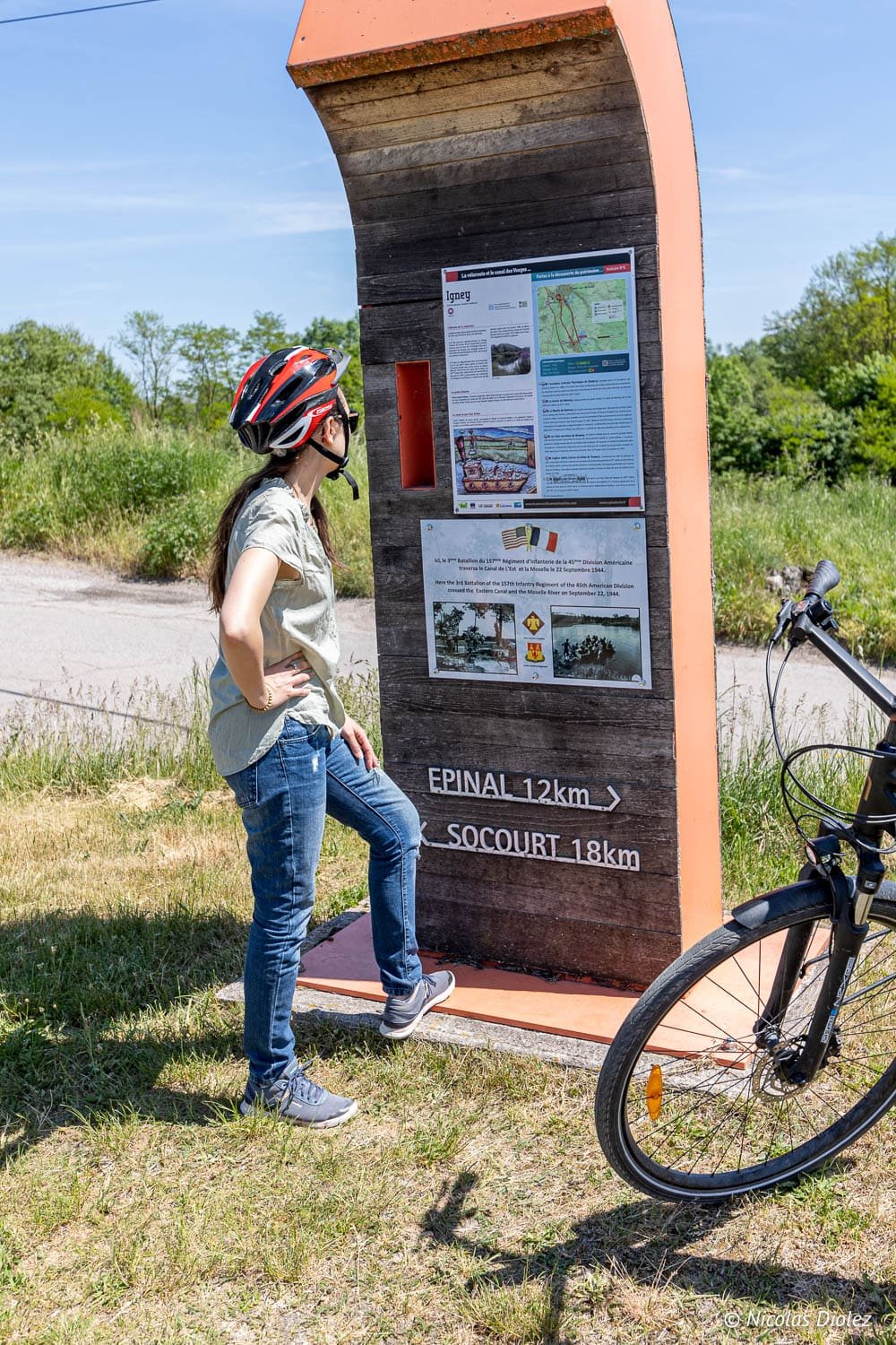 Cycliste consultante panneau indicateur Épinal 12km Socourt 18km vélo.