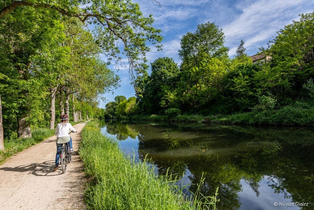 Cycliste sur chemin de halage près d'un canal verdoyant près d'Épinal.
