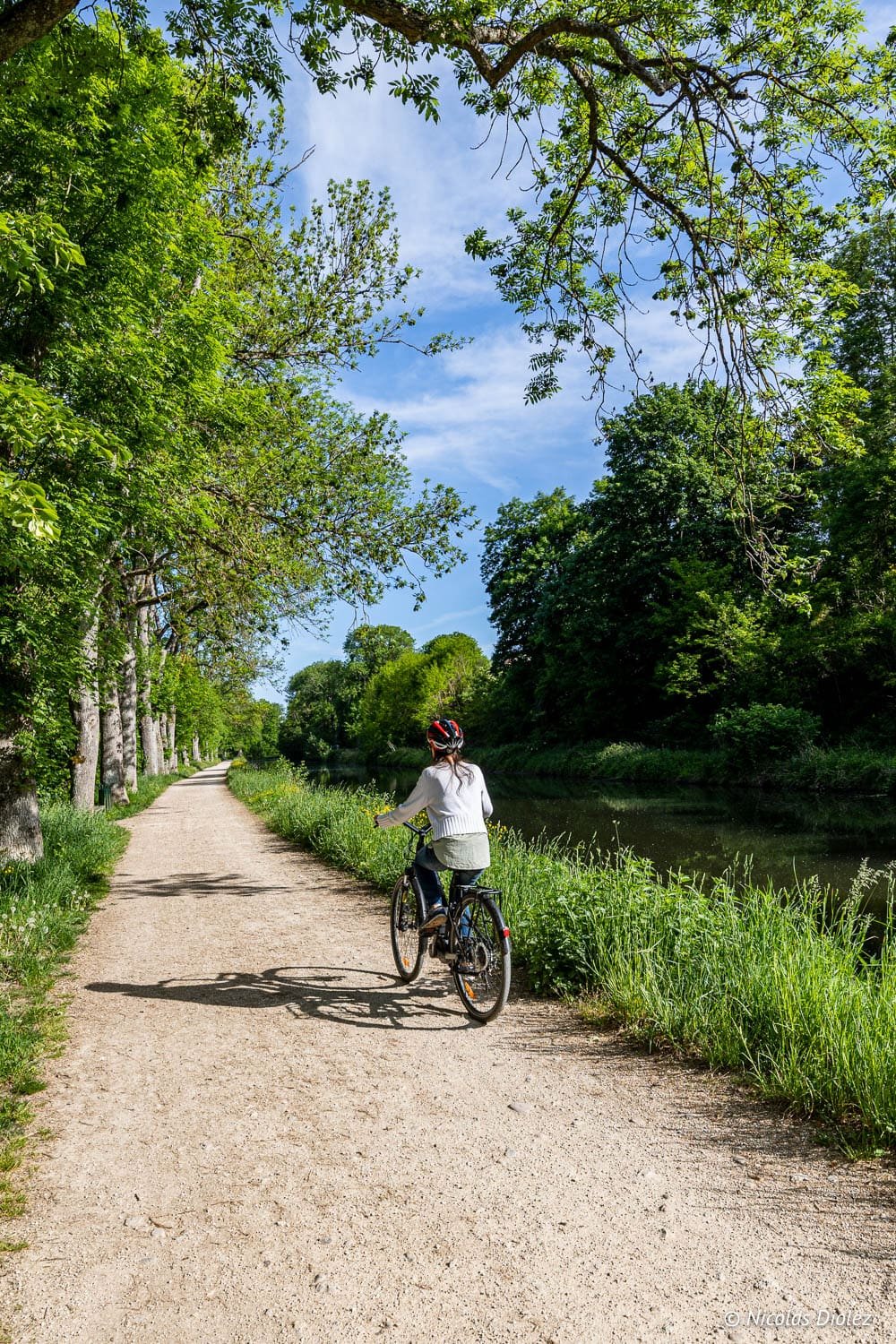 Cycliste sur chemin de halage bordant un canal près d'Épinal.