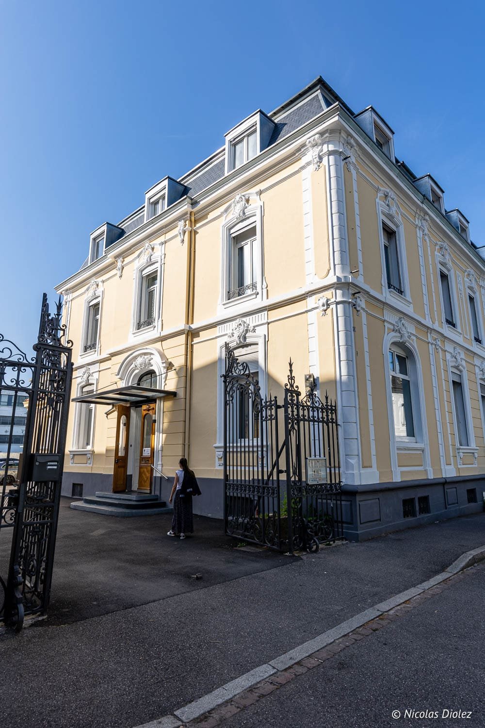 Hôtel Berti Mulhouse façade jaune avec portail en fer forgé pour séjour.