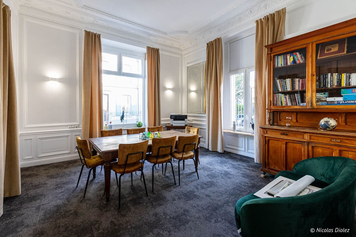 Salle de réunion ou petit salon de l'Hôtel Berti à Mulhouse avec table et bibliothèque.