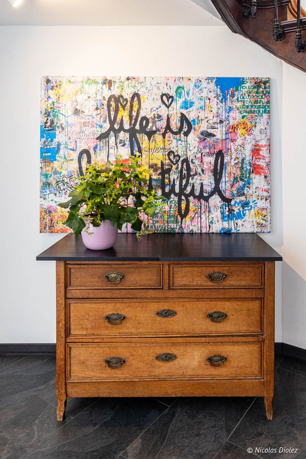 Commode ancienne sous tableau street art "Life is Beautiful" à l'Hôtel Berti Mulhouse.