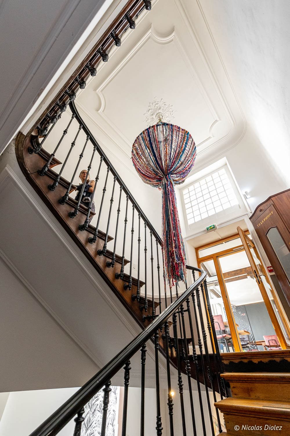 Escalier ancien avec balustrade en fer forgé et lustre coloré dans un bâtiment de Mulhouse.