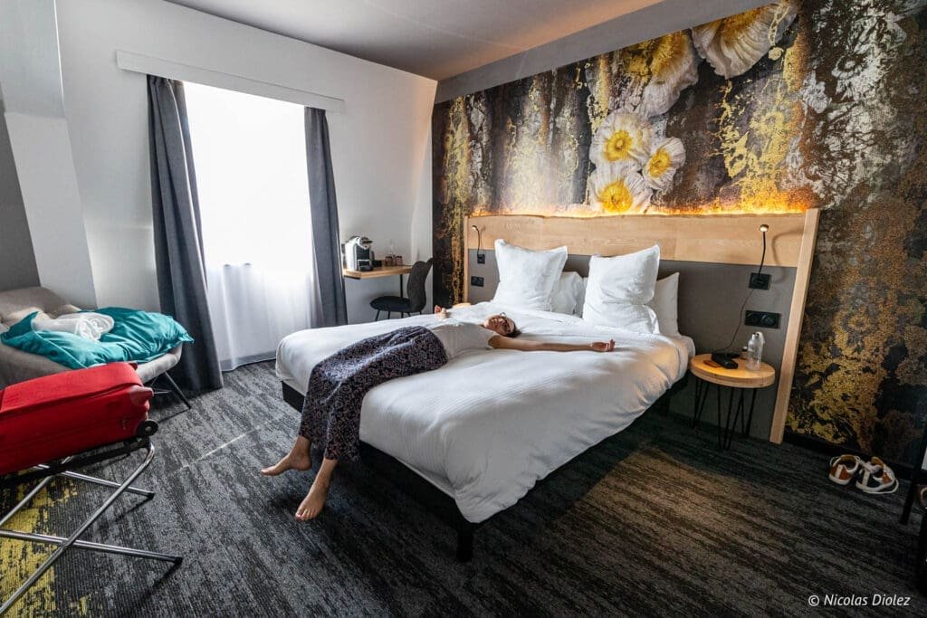 Femme se relaxant sur le lit d'une chambre d'hôtel à Mulhouse.