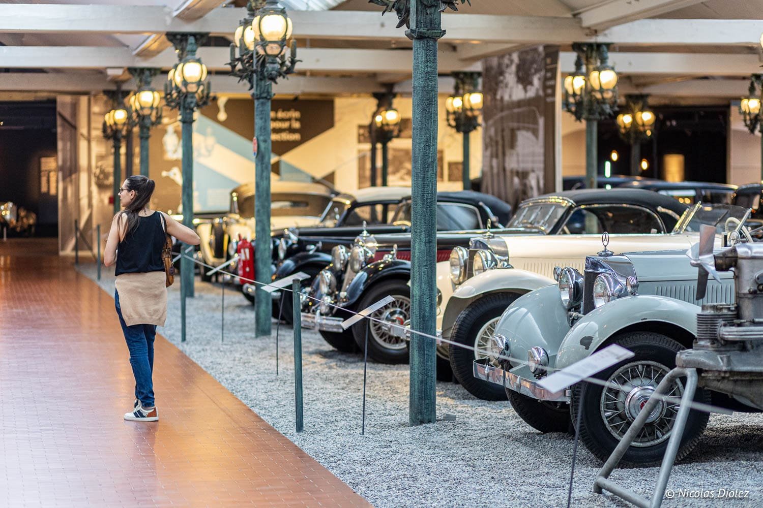 Visite Musée National de l'Automobile Mulhouse, femmes observant voitures anciennes.