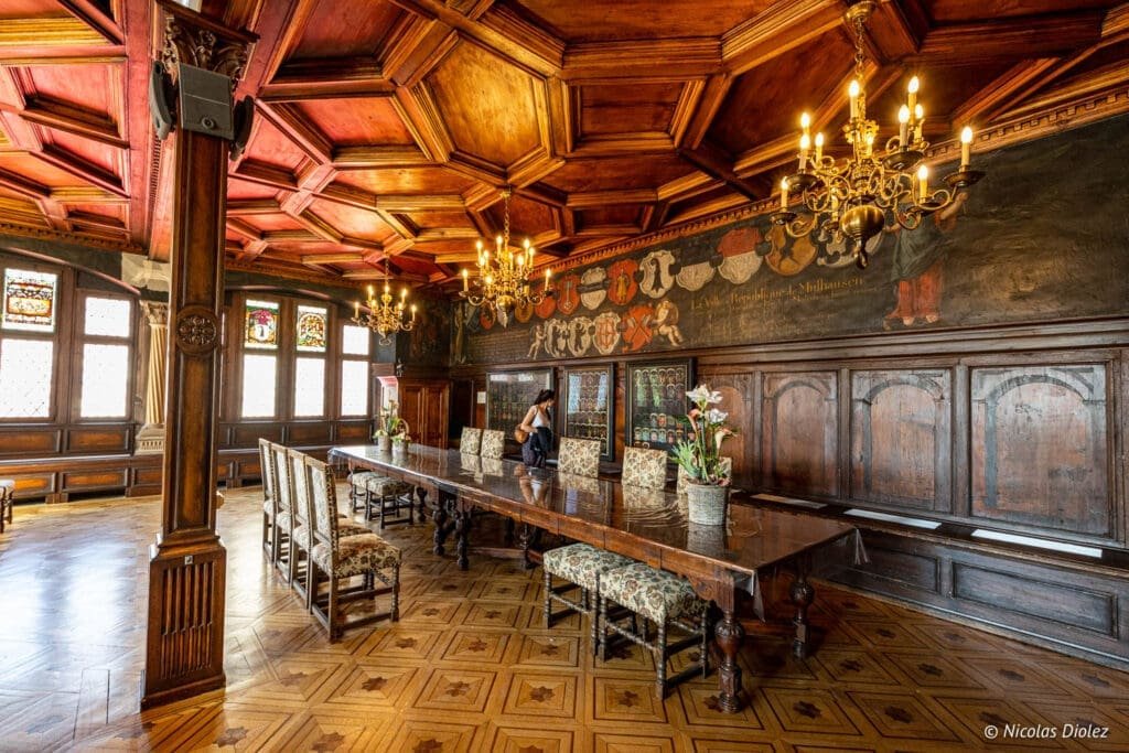 Intérieur boisé richement décoré du Musée Historique de Mulhouse avec longue table.