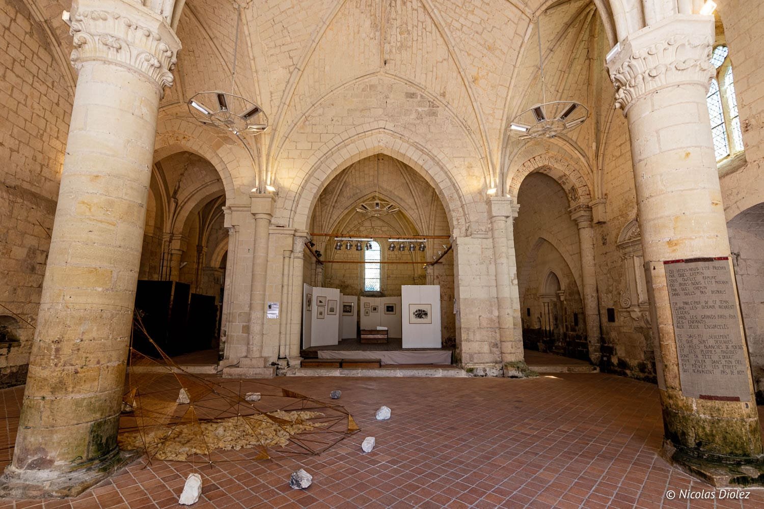 Intérieur d'édifice religieux avec voûtes gothiques et exposition d'art contemporain.