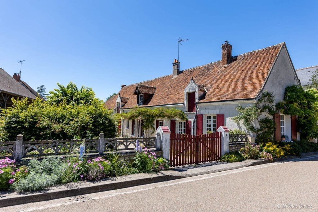 Traditional house with red shutters and flower garden in Chédigny, South Touraine.