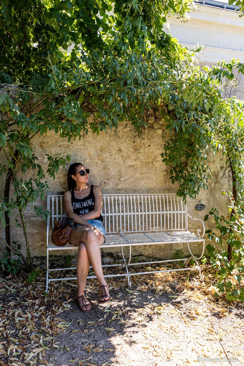 Femme se reposant sur un banc blanc sous la végétation à Chédigny, Sud Touraine.